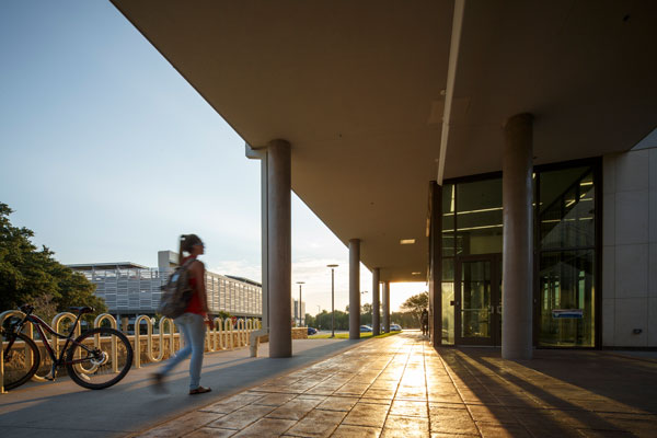 FD-Tech student walking in front of the Jindal School of Management building
