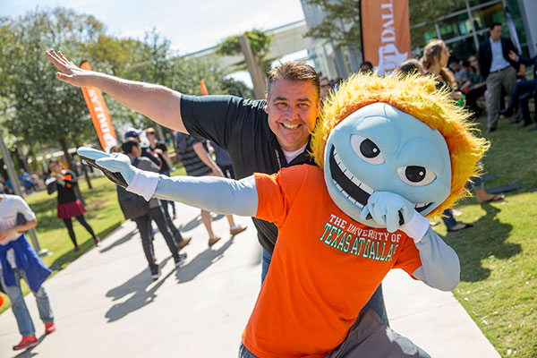 Jindal School student whooshing with mascot Temoc on the UT Dallas campus